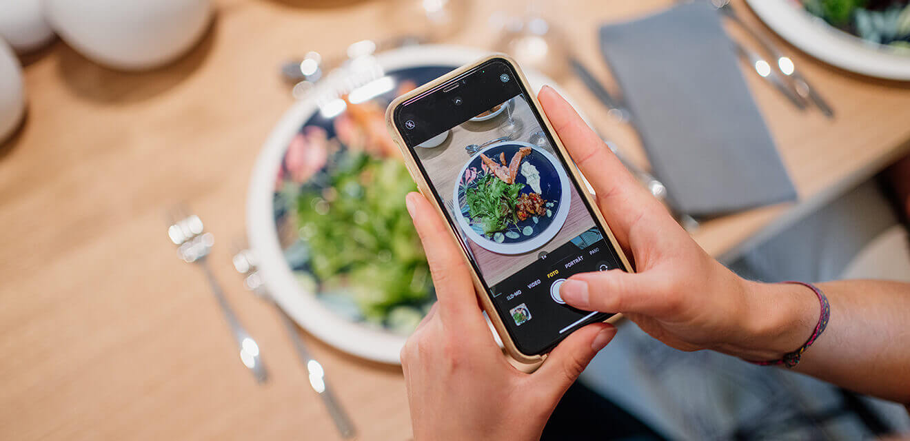 Ein Teilnehmer fotografiert stolz sein Essen mit dem Smartphone. 
